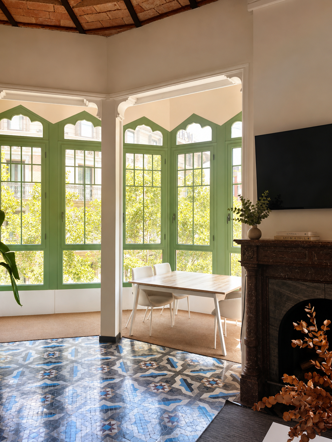 Bright studio interior with green arched windows, a wooden table, and a fireplace